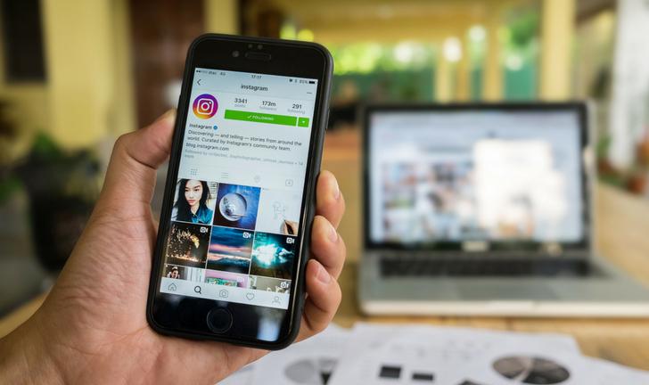 Mão segurando celular logado no Instagram